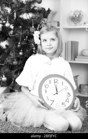 Bambina orologio di contenimento in prossimità di albero di natale in camera Foto Stock