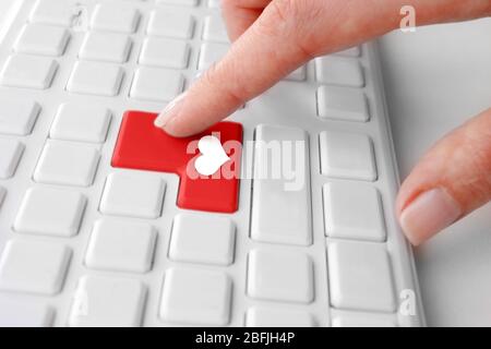 Mano femminile che digita sulla tastiera con l'icona a forma di cuore, primo piano Foto Stock