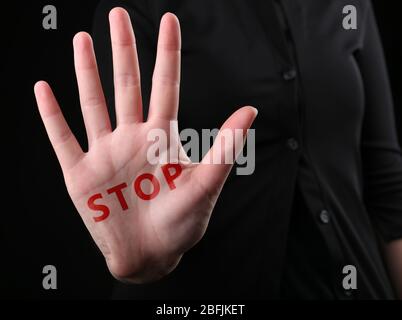 Mano femminile con stop di parola su sfondo nero Foto Stock