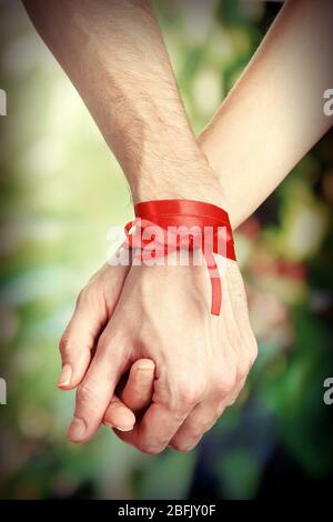 Mani di uomo e donna legate con nastro su sfondo luminoso Foto Stock