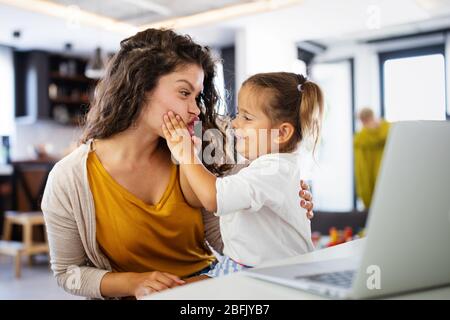 Madre a casa cercando di lavorare con il bambino a distrarre il suo Foto Stock