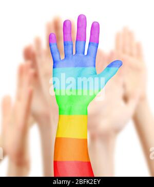 Mano dell'uomo dipinta come la bandiera arcobaleno sullo sfondo delle altre mani Foto Stock