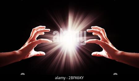 Mani umane con luce su sfondo nero Foto Stock