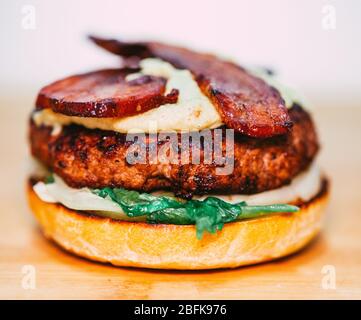 Gourmet di formaggio Bacon hamburger con insalata fresca e carne cruda. Mani in mano Foto Stock