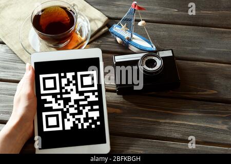 Mano che tiene il PC tablet con codice QR sullo schermo Foto Stock