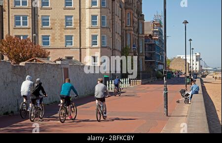 Portobello Beach, Edimburgo, in bicicletta Scozia. 19 aprile 2020. La gente fuori prendendo il loro excercise quotidiano sulla spiaggia in tempo luminoso di sole, una nuotatrice selvaggia femminile che affronta il surf frisy, meno gente che ieri mentre il Lockdown di Coronavirus continua, Tuttavia, la Promenade era affollata di ciclisti come sempre, più della spiaggia, anche se la spiaggia di sabbia può essere più facile per gli escursionisti isolarsi da soli. Temperatura di 10 gradi con un vento ENE di 17km/h potenziale raffica di 33km/h. Credit: Arch White/Alamy Live News. Foto Stock