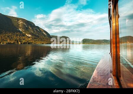 Barca a vela sul lago di Bohinj in estate, famosa meta di viaggio in Slovenia Il parco nazionale del Tricorno visto dalla barca elettrica Foto Stock