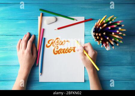 Concetto di lavoro da sogno. Mani con matite colorate e foglio di carta su tavola di legno Foto Stock
