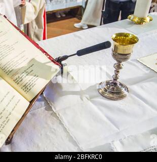 Calice con vino, consacrato nel sangue di Cristo risorto, pronto alla comunione dei fedeli durante la messa Foto Stock