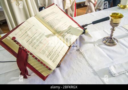 calice con vino, sangue di cristo e libro di messa sull'altare della chiesa Foto Stock