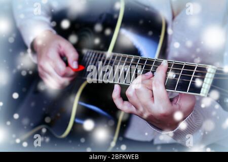 Chitarra acustica in mani femminili sopra effetto neve Foto Stock