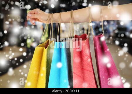 Mano femminile con borse di carta per lo shopping sul mercato sopra effetto neve Foto Stock