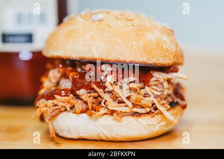 Hamburger barbecue di maiale caldo con mani e birra fresca su un set di legno Foto Stock