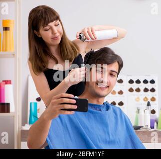 Il giovane uomo attracrive visitando barbiere femmina Foto Stock