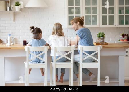 Vista posteriore mamma sorridente che alimenta le verdure della figlia. Foto Stock