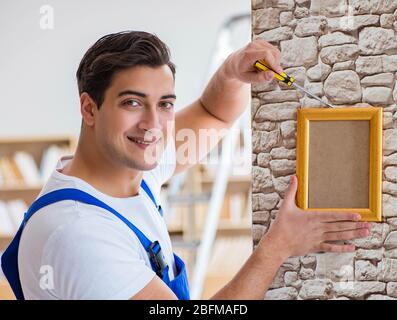 Il riparatore che mette cornice di immagine sulla parete Foto Stock