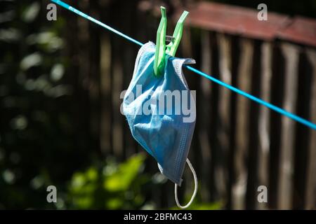 Una maschera facciale lavata si appende su una linea di clothesline ad asciugare durante la crisi del coronavirus. Foto Stock