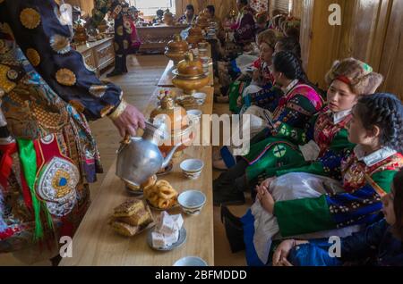 Uomo che serve cibo a bridesmaids in una festa buddista matrimonio. Shangri la China 2019 Foto Stock