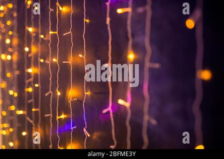 Parte di scintillanti ghirlande o luci appese lungo il muro in night club o casa decorata per una vacanza o un evento di celebrazione Foto Stock