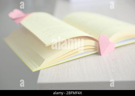 Libro e origami cuore come segnalibri su tavola di legno Foto Stock