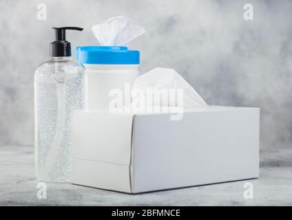 Contenitore in plastica con salviette imbevute di alcol con contenitore in plastica igienizzante per le mani e scatola di tessuti su sfondo bianco. Protezione ottimale da tutti i virus. Foto Stock