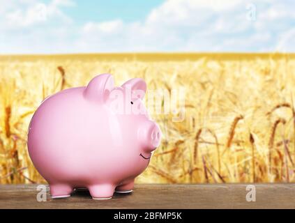 Piggy banca su tavolo di legno, campo sfondo Foto Stock
