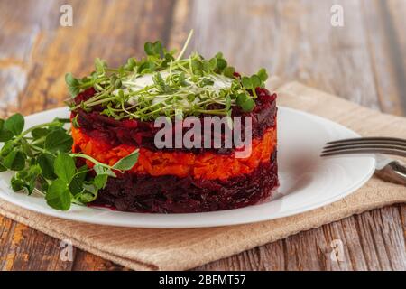 Un'insalata di detox sana con barbabietole, carote, microgredi e uvetta. Cibo vegetariano vegano su sfondo di legno. Foto Stock