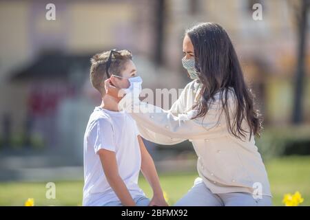 Giovane donna che mette una maschera sul viso su un maschio giovane in una giornata di sole in città. Foto Stock