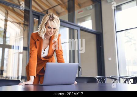 Bella donna d'affari che si stella al suo schermo del laptop Foto Stock