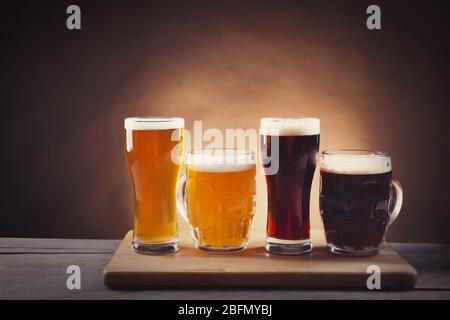 Diversi tipi di birra alla spina in bicchieri su tavolo di legno. Stilizzazione retrò Foto Stock