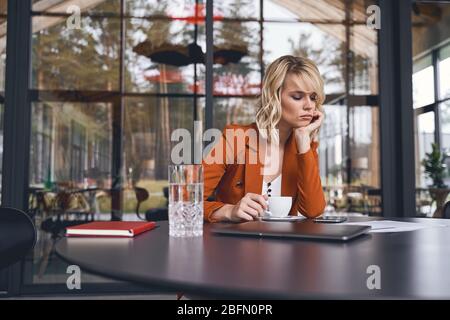 Giovane donna depressa seduta alla scrivania Foto Stock