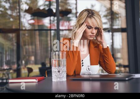 Giovane donna a basso contenuto di spirito seduto alla scrivania Foto Stock
