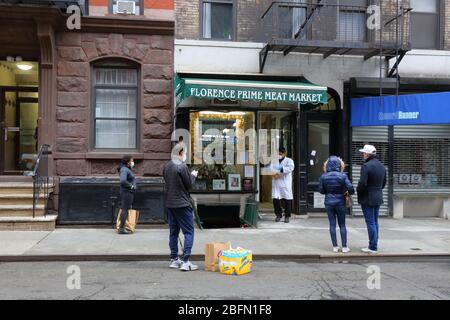 Persone sociali che si distanziano e indossano maschere come si aspettano per entrare in un macelleria durante coronavirus COVID-19. New York, 18 aprile 2020. Foto Stock