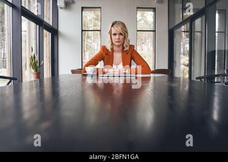 Donna bionda seria seduta nel suo ufficio Foto Stock