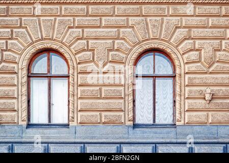Due finestre ad arco sullo sfondo di pareti beige con intonaco decorativo testurizzato. Dalla serie Windows di San Pietroburgo. Foto Stock