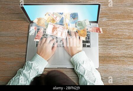 Concetto finanziario. Fare soldi su Internet. Donna che lavora con un computer portatile su una scrivania in legno. Vista dall'alto Foto Stock