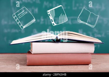 Libri su tavola di legno su sfondo lavagna con icone vettoriali Foto Stock