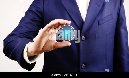 Uomo d'affari che tiene l'orologio in mano su sfondo chiaro Foto Stock