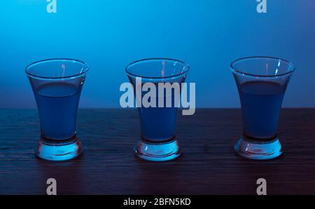 Tre bevande al party. Tre shot con cocktail al bar. Liquore, vodka, fresco. Brillante su uno sfondo colorato. Night club, dopo la festa. Foto Stock