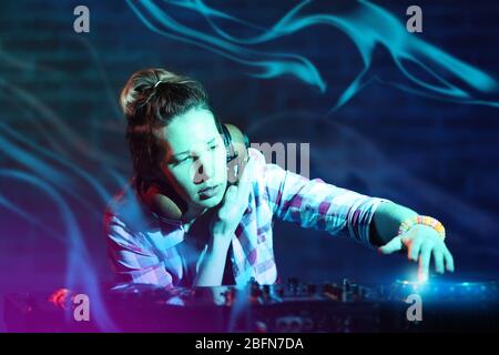 DJ che suona musica al mixer su sfondo muro di mattoni sfocati Foto Stock