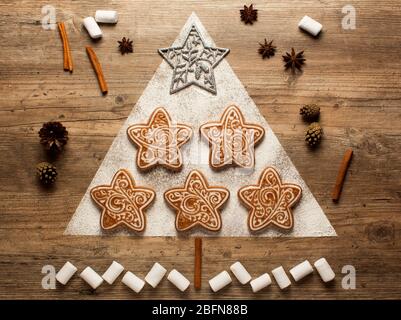 Biscotti di Natale e taglierine di biscotti su sfondo di legno. Composizione di Natale. Inverno, concetto di nuovo anno. Disposizione piatta, vista dall'alto. Coni, cannella, coria Foto Stock