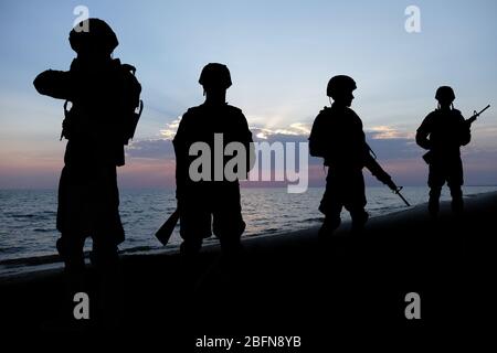 Silhouette di soldati su sfondo tramonto. Concetto di servizio militare. Foto Stock