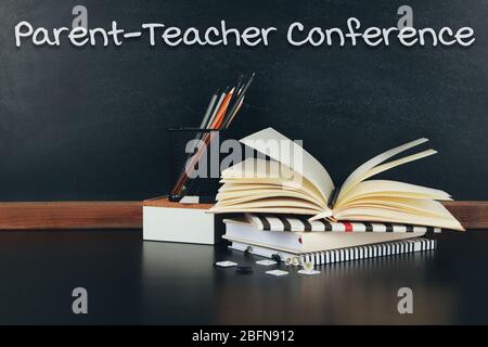 Fermo sul tavolo. Testo CONFERENZA GENITORE-INSEGNANTE su sfondo lavagna. Concetto scolastico. Foto Stock