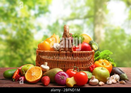 Verdure fresche e frutta su tavola di legno contro sfondo naturale Foto Stock