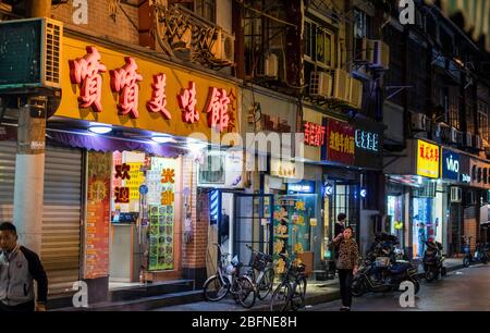 Una fila di negozi e negozi di alimentari da asporto, raffigurati di notte nel centro di Shanghai, Cina Foto Stock