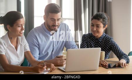 Tre diversi compagni di squadra che guardano lo schermo del computer per discutere il progetto Foto Stock