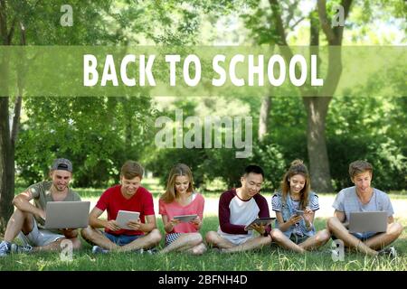 Giovani che utilizzano dispositivi moderni per studiare all'aperto. Testo DI RITORNO A SCUOLA sullo sfondo Foto Stock