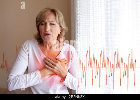 Donna matura che soffre di un attacco di cuore a casa Foto Stock