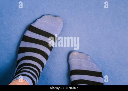 Gambe uomo in calze a righe. Calzini con strisce nere e blu. Un uomo è in piedi su carta colorata Foto Stock