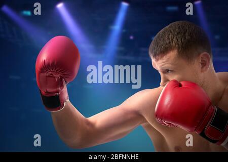 Giovane uomo con guanti da boxe su sfondo scuro Foto Stock